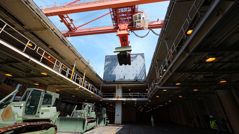 A U.S. Marine Corps Maritime Prepositioning Force crawler dozer aboard the United States Naval Ship Seay (T-AKR 302) Is hoisted off using a gantry crane in preparation for the Maritime Prepositioning Force Maintenance Cycle (MMC) 14 at Marine Corps Support Facility Blount Island.