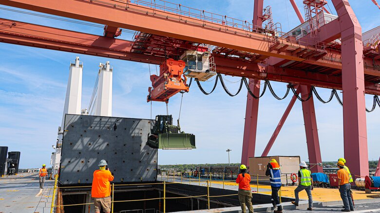 A U.S. Marine Corps Maritime Prepositioning Force crawler dozer aboard the United States Naval Ship Seay (T-AKR 302) Is hoisted off using a gantry crane in preparation for the Maritime Prepositioning Force Maintenance Cycle (MMC) 14 at Marine Corps Support Facility Blount Island.