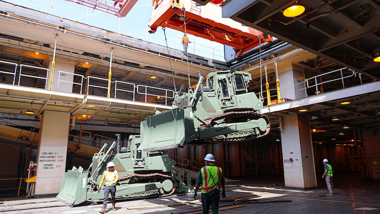 A U.S. Marine Corps Maritime Prepositioning Force crawler dozer aboard the United States Naval Ship Seay (T-AKR 302) Is hoisted off using a gantry crane in preparation for the Maritime Prepositioning Force Maintenance Cycle (MMC) 14 at Marine Corps Support Facility Blount Island.