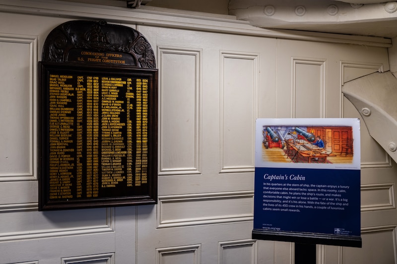 A plaque with golden names hangs on a white wall.