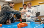 True Soria, a computer scientist at the Naval Surface Warfare Center Dahlgren Division (NSWCDD), mentors students at King George Middle School during Robotics Week. This program is part of NSWCDD's K-12 STEM Outreach initiatives, highlighting the organization's commitment to supporting in-class robotics workshops and lessons facilitated by NSWCDD engineers at local schools. (Dorina Watermolen/NSWCDD photo)