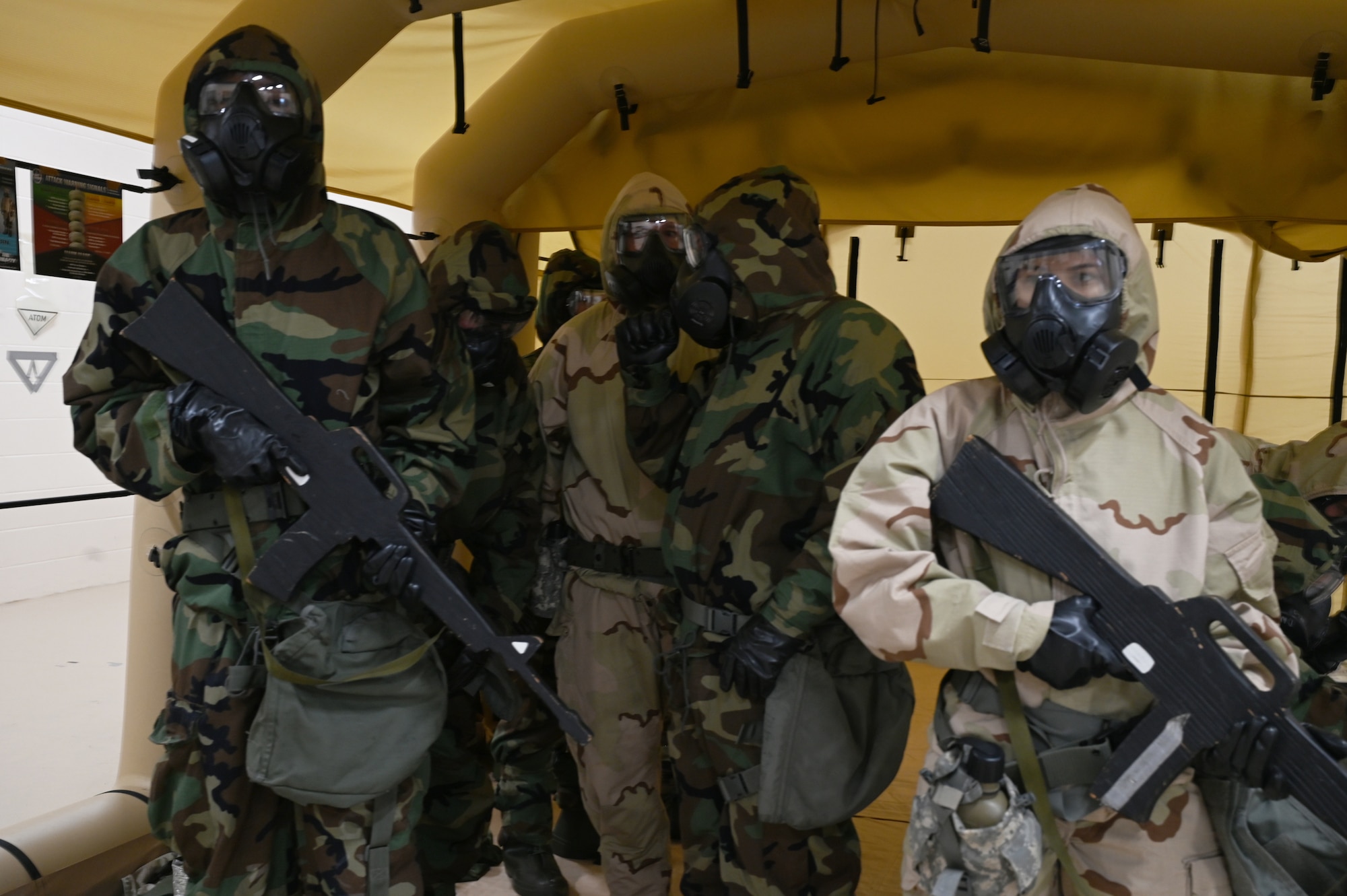 Airmen wear Mission Oriented Protective Posture gear and perform job duties.