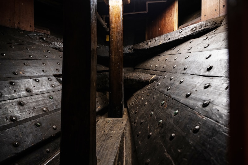 Wooden structures are next to beams inside of a ship.