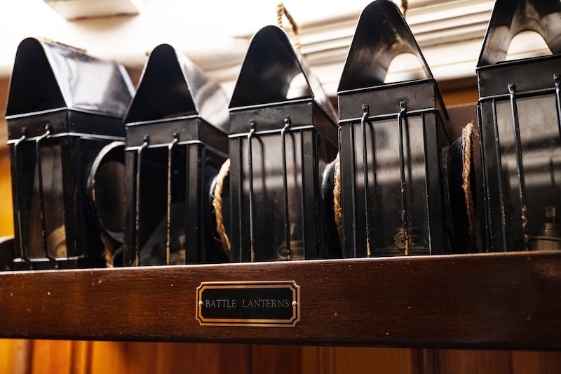 A row of battle lanterns sits on a wooden shelf.