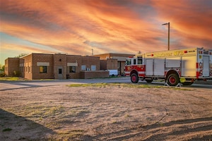 A fire truck is parked outside of a space force base with a sunset overhead