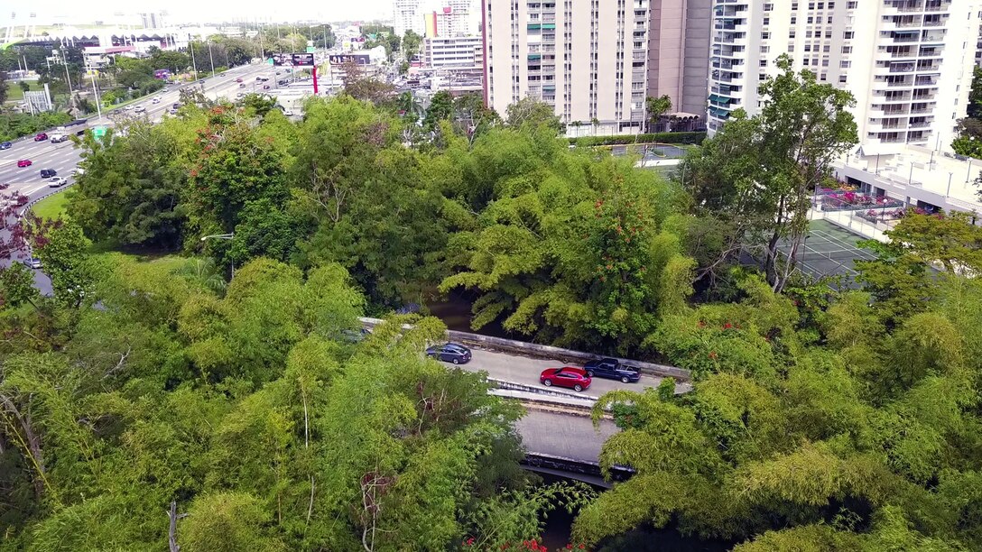 Aerial view of two bridges crossing a river near condominium buildings and an expressway.