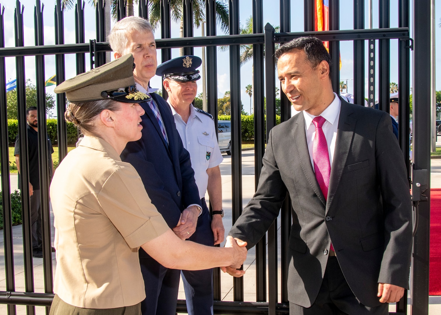 A woman in a military uniform shakes hands with a man in a black suit.