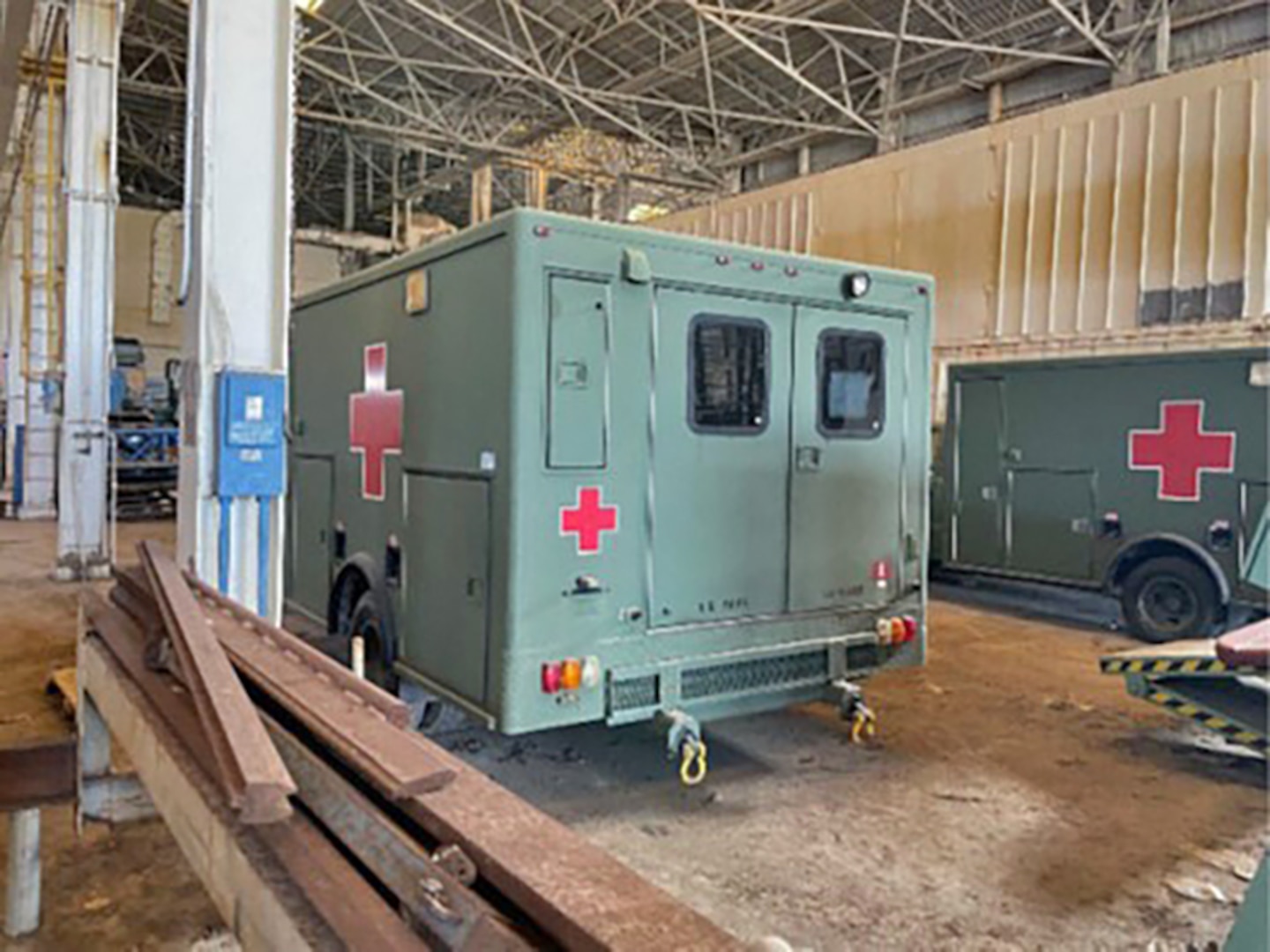 Military field ambulances parked in a warehouse.