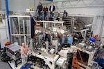 Members of the Laser Plasma Branch at the U.S. Naval Research Laboratory join visitors from fellows defense research agencies for a group photo in the NIKE target area in Washington, D.C., Oct. 25, 2024. The visit featured a tour of the NIKE laser facility to promote potential collaborative experiments in reactive materials research. (U.S. Navy photo by Sarah Peterson)