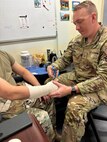 U.S. Air National Guard Senior Master Sgt. Bryan Sdankus, assigned to the 158th Fighter Wing, applies a bandage.