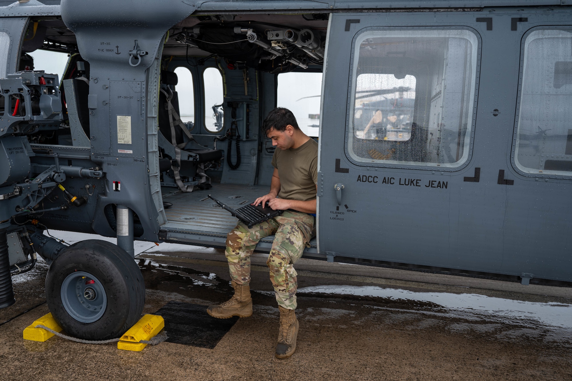 A U.S. Air Force Airman sits in an HH-60W Jolly Green II.