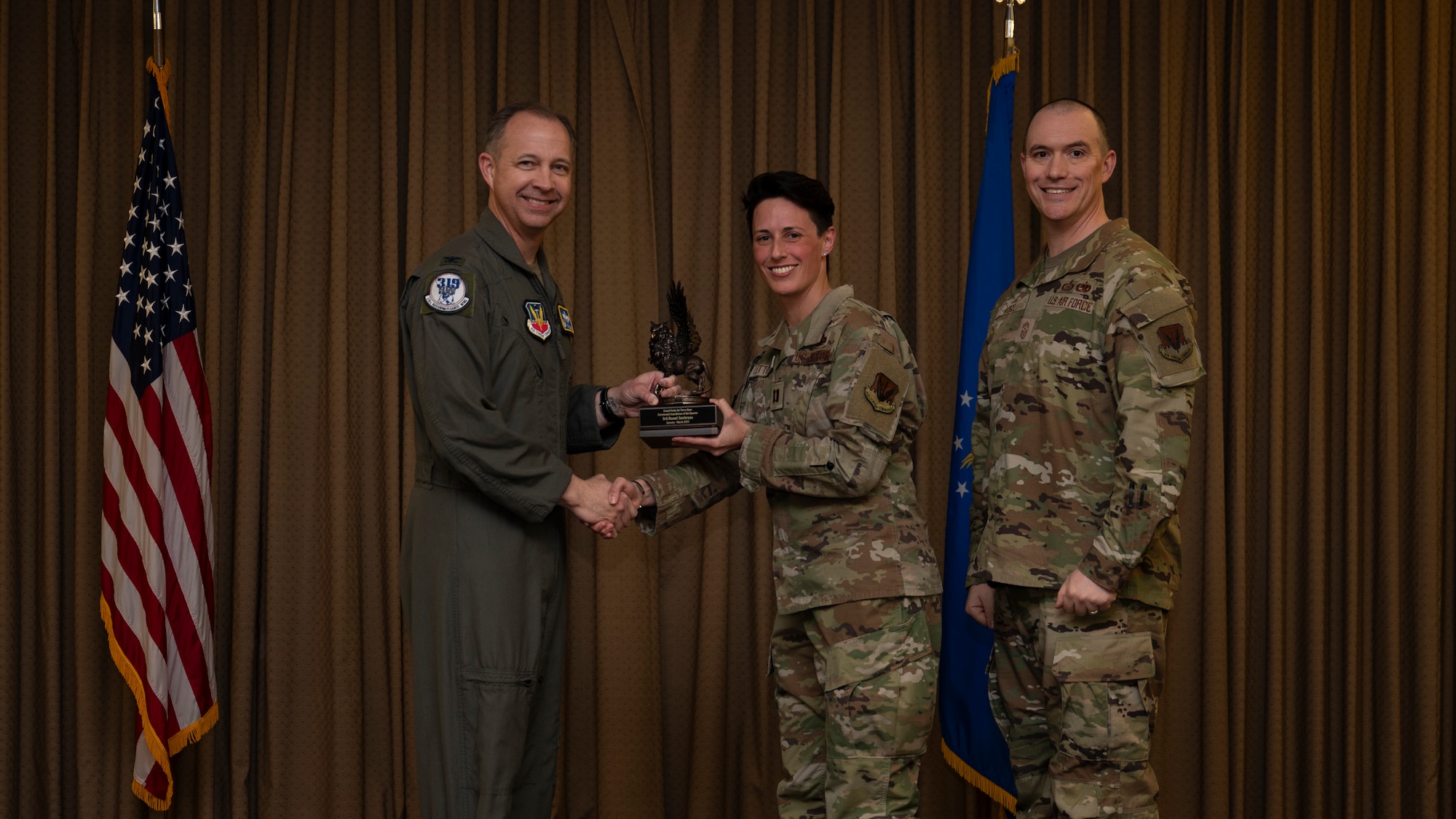 Capt. Nikita Lettunich, Director of Operations of the 319th Communications Squadron accepts the Ceremonial Guardsman of the Quarter Award on behalf of Senior Airman Russel Sambrano, 319th Communications, during the 319th Reconnaissance Wing’s 1st quarter award ceremony at Grand Forks Air Force Base, North Dakota, May 2, 2025.