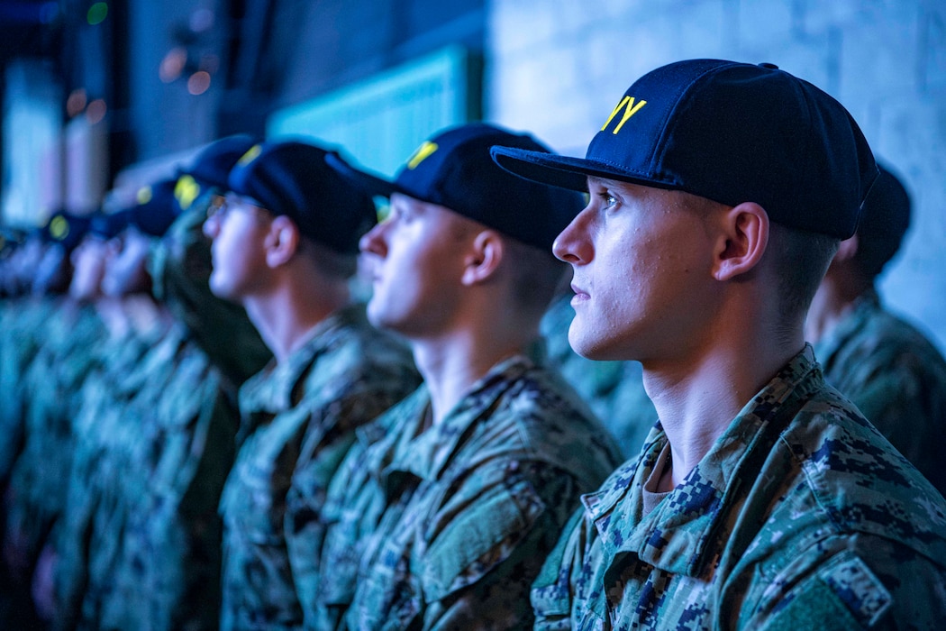 Recruits gather in formation on the USS Trayer’s pier during their capping ceremony at Recruit Training Command. Known as "Battle Stations," this final challenge tests essential naval skills before graduation. Over 40,000 recruits train here annually.