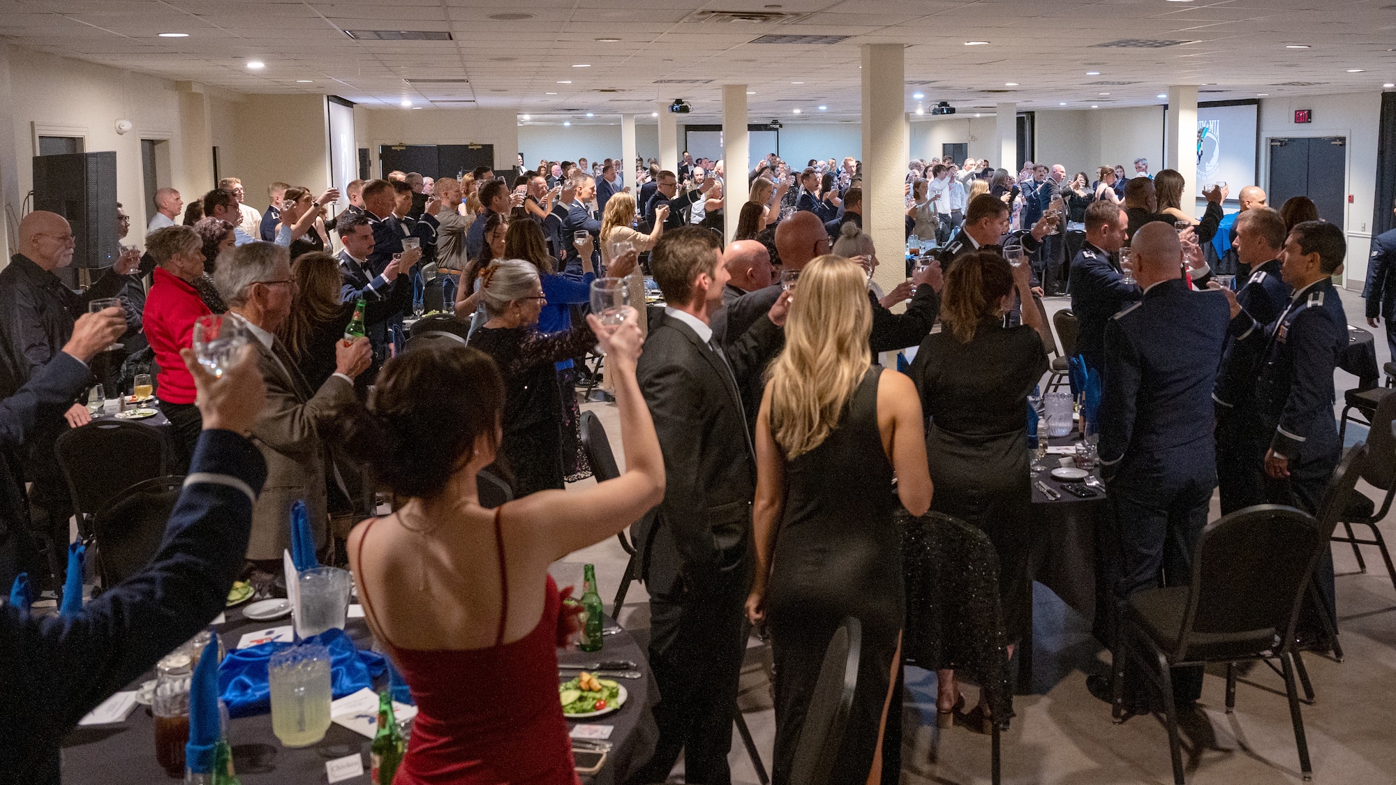 Attendees at the UPT Class 25-09 Graduation raise their glasses in salute to fallen pilots at Laughlin Air Force Base, Texas, May 1, 2025. The salute originated from Navy Captain Jerry Coffee while he was in a Vietnamese prison cell, where he noticed a formation of 4 F-105s during a bombing run. The lead aircraft was trailing smoke and the rest of the flight pulled away, leaving the damaged aircraft alone. After it had passed and presuming the worst, he wrote a toast to the unfortunate pilot and all those who had gone before him. (U.S. Air Force photo by Staff Sgt. Nicholas Larsen)