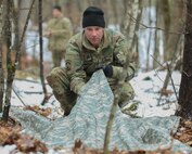 Sgt. Matthew Witcher, a fuel supply specialist with Charlie Company, 3rd Battalion, 238th Aviation Regiment (MEDEVAC), builds a shelter during a search and rescue field training exercise April 12, 2025, at the Edward Cross Training Complex in Pembroke. Soldiers from the NHARNG company practiced building shelters during a final evasion tactics event.