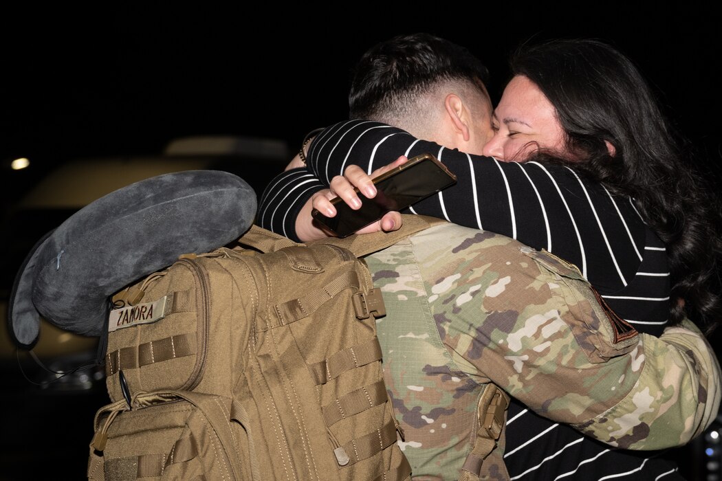 a wife and husband hug upon reuniting after husbands return from deployment