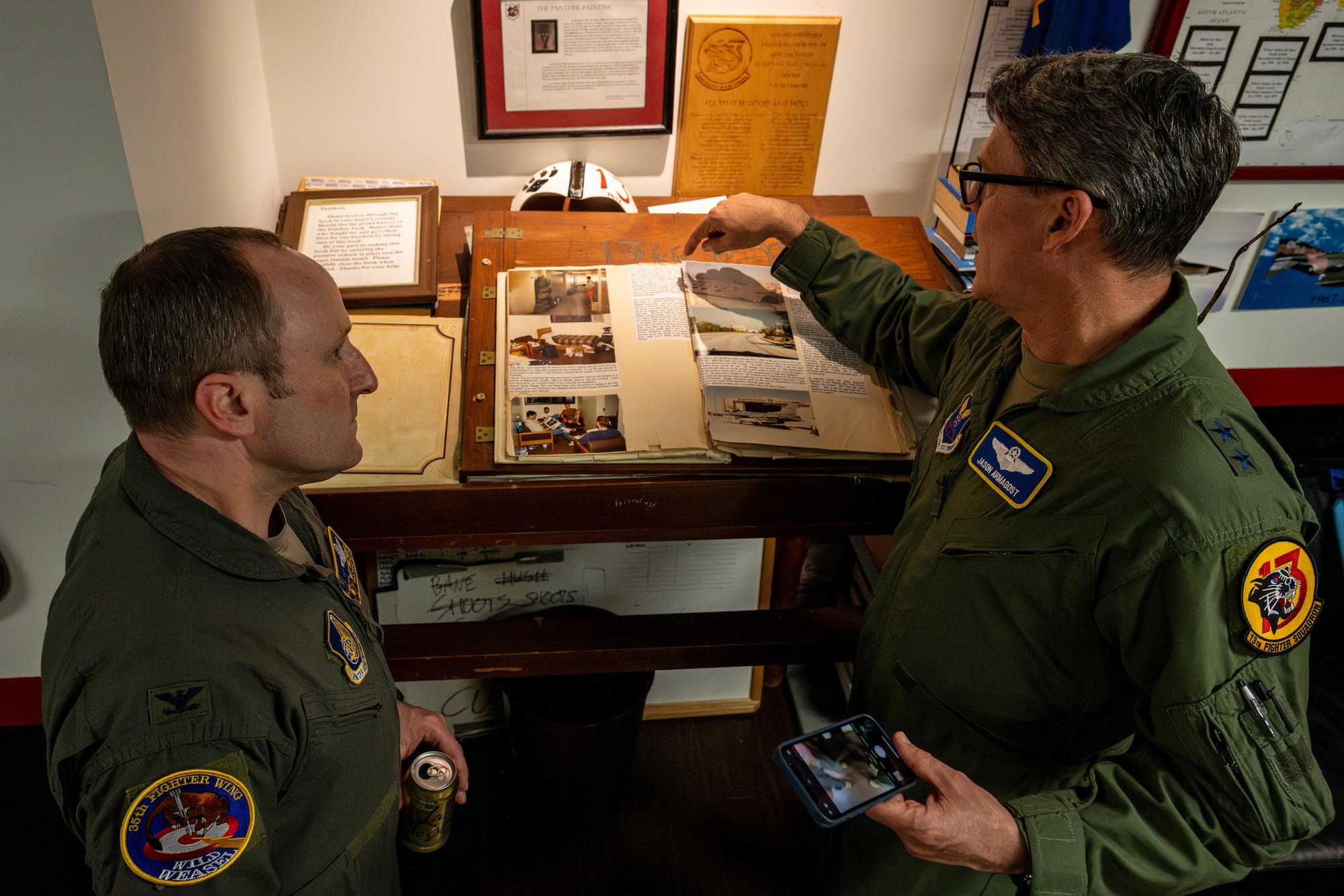 U.S. Air Force Maj. Gen. Jason Armagost, commander Eighth Air Force and Joint-Global Strike Operations Center, shows Col. Matthew Kenkel, 35th Fighter Wing deputy commander, photos from the World's Greatest Wild Weasels book during an immersion tour