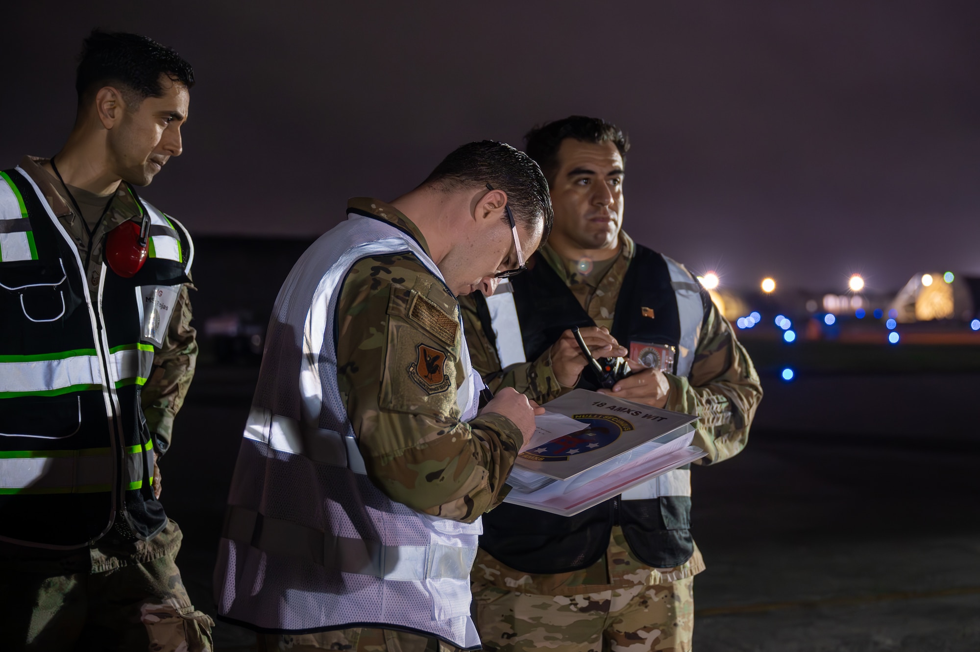 Service members service an aircraft at night.