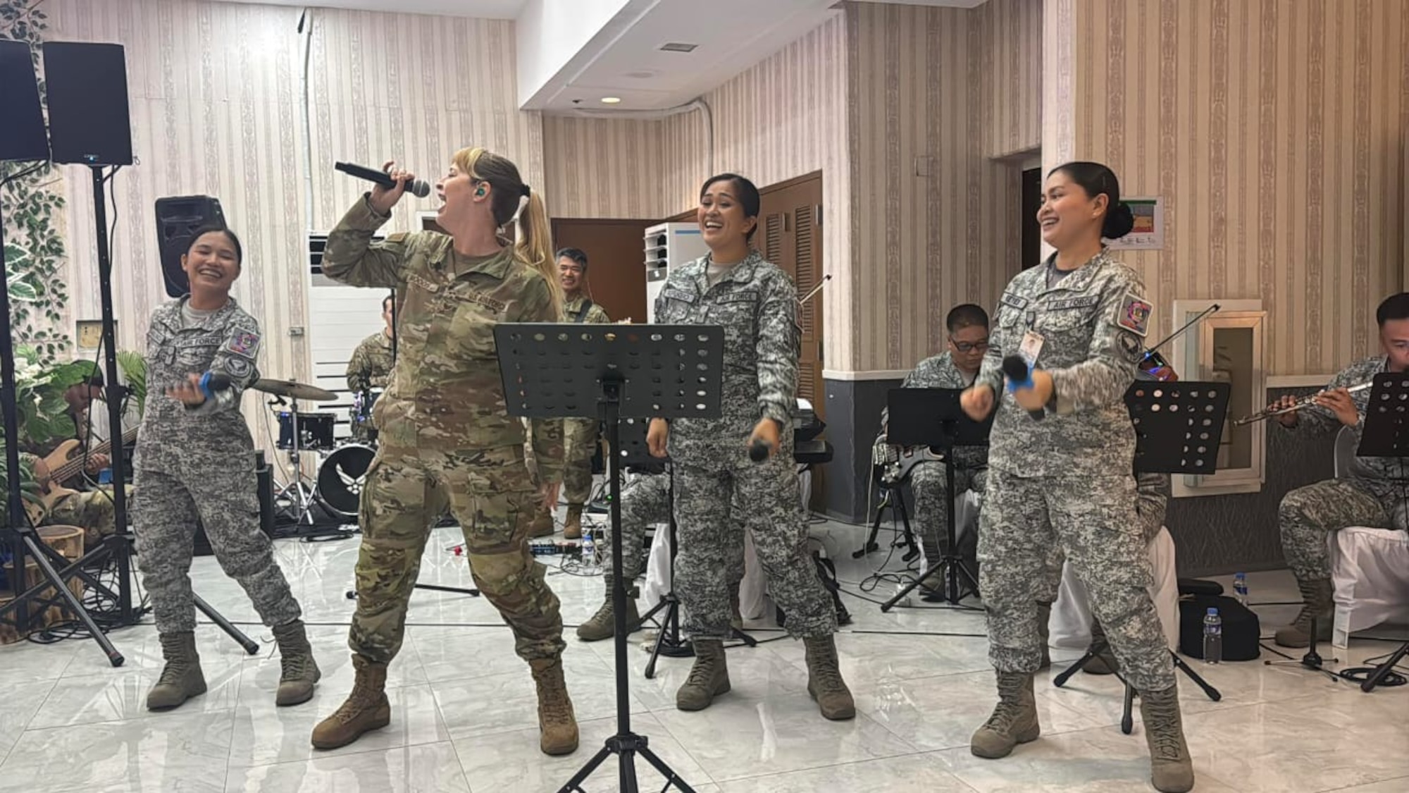 Four women in military uniform sing together during a music performance.