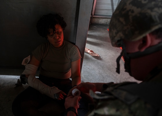 A military medical professional performs medical care on a patient.