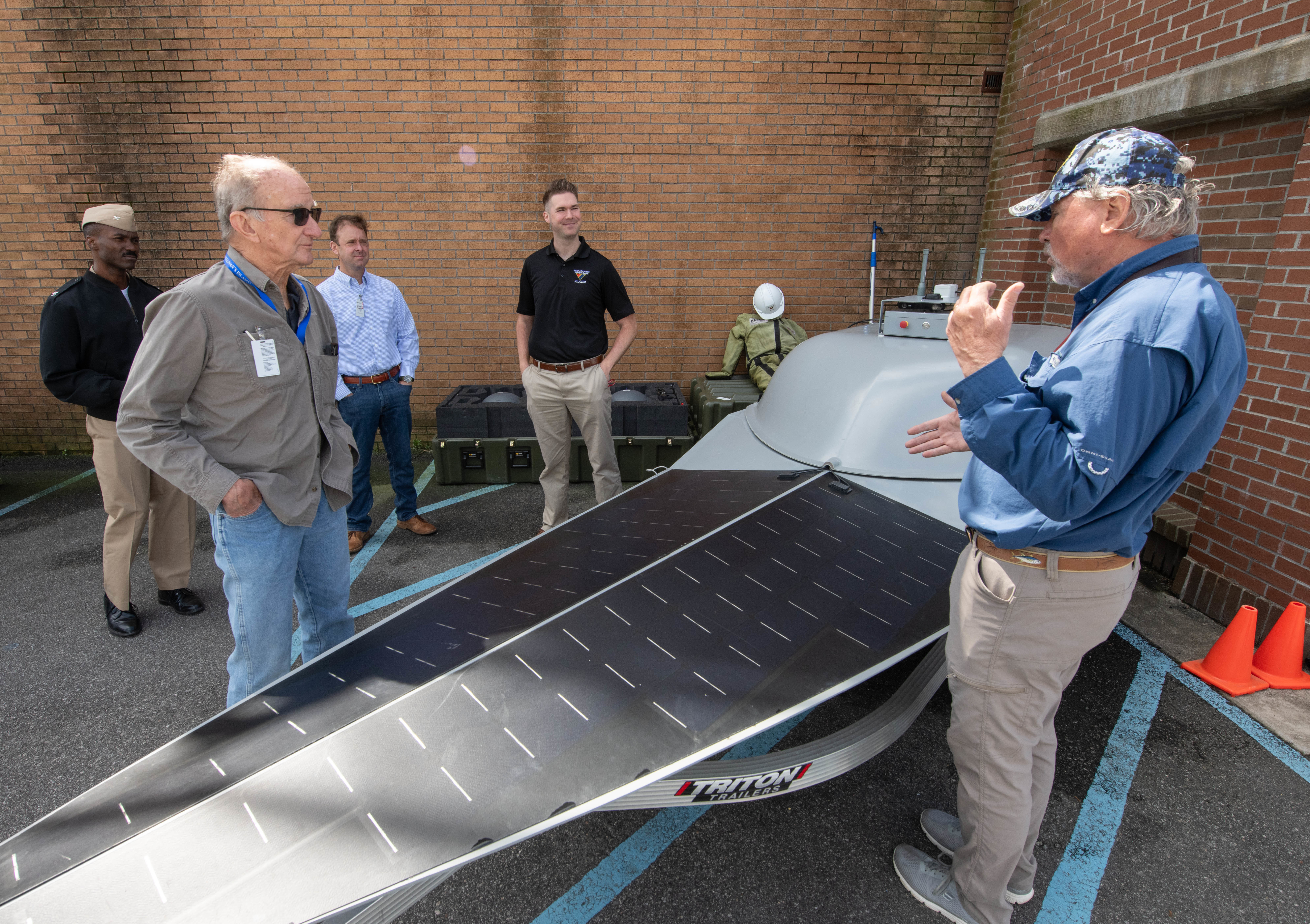 Naval Information Warfare Center (NIWC) Atlantic employee Jay Hughes (right) discusses NIWC’s facility and the role it plays in an upcoming experiment called Southern Lightning which is being held on Sullivan’s Island with the Mayor Patrick O’Neil (sunglasses) and Town Administrator Joe Henderson (light blue shirt) along with NIWC’s commanding officer Captain Matthew O’Neal and NIWC employee Christian Martin.