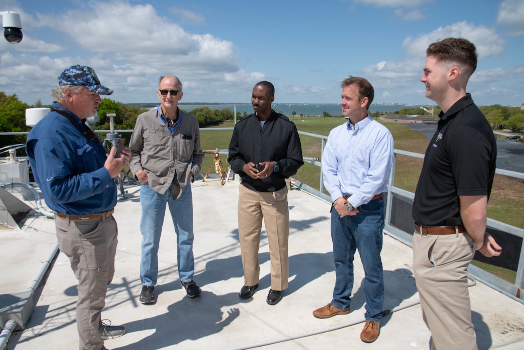 Naval Information Warfare Center (NIWC) Atlantic employee Jay Hughes (right) discusses NIWC’s facility and the role it plays in an upcoming experiment called Southern Lightning which is being held on Sullivan’s Island with the Mayor Patrick O’Neil (sunglasses) and Town Administrator Joe Henderson (light blue shirt) along with NIWC’s commanding officer Captain Matthew O’Neal and NIWC employee Christian Martin.