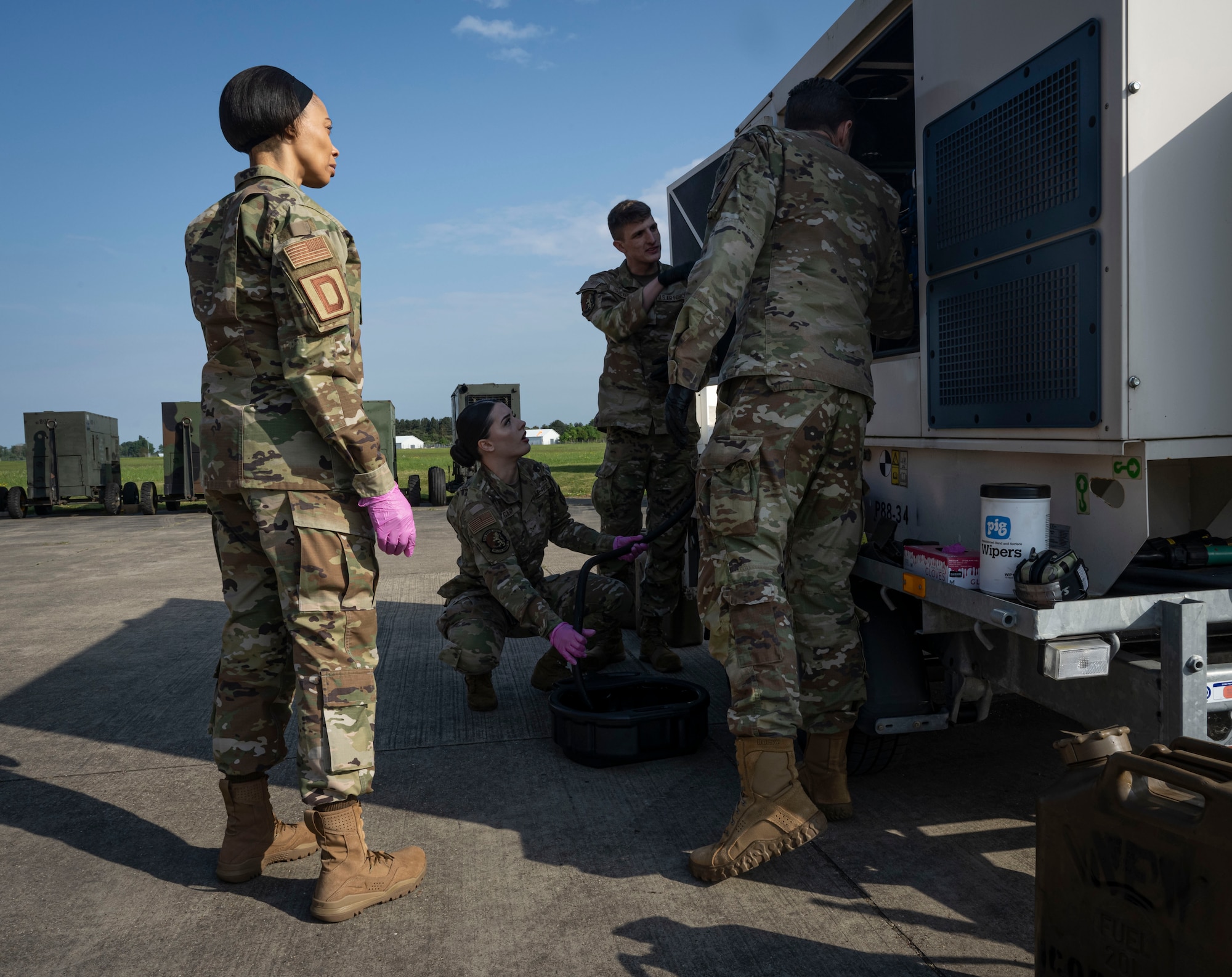 U.S. Air Force Col. Ryan Garlow, right, 100th Air Refueling Wing commander, and Chief Master Sgt. Tiffany Griego, left, 100th ARW command chief, watch Airmen prepare a generator for maintenance during a Day in the Life immersion at RAF Mildenhall, England, May 2, 2025.