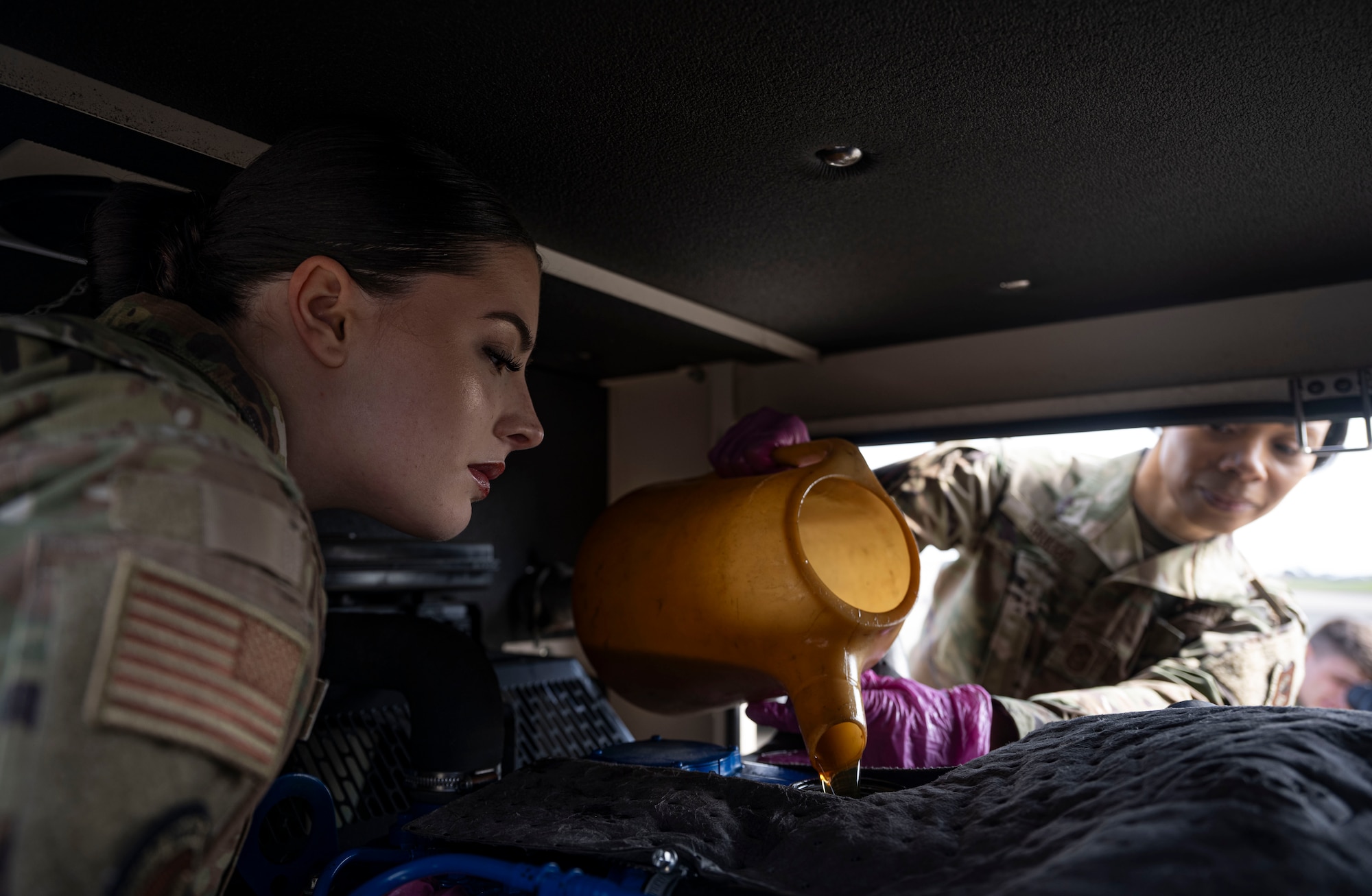 U.S. Air Force Airman 1st Class Gracie Gary, left, 100th Civil Engineer Squadron power production journeyman, watches Chief Master Sgt. Tiffany Griego, 100th Air Refueling Wing command chief, as she pours oil into a generator reservoir at RAF Mildenhall, England, May 2, 2025.