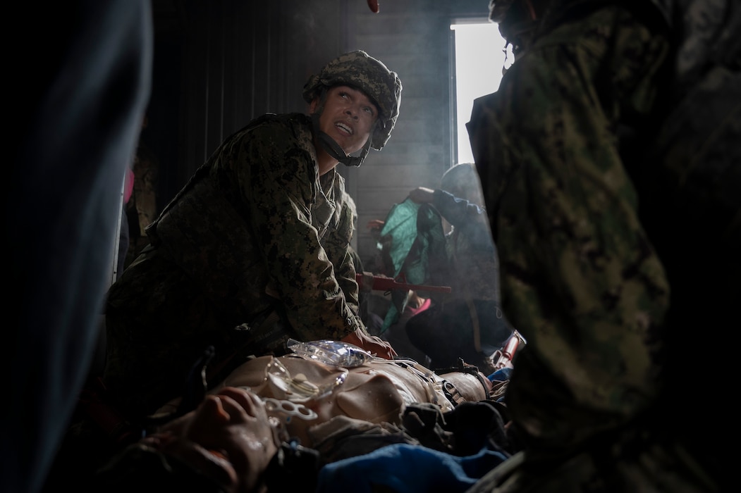 250403-F-JB191-1415 U.S. Navy Hospital Corpsman 2nd Class Maliq Webster, assigned to the Whidbey Island-class dock landing ship USS Rushmore (LSD 47), performs critical medical care on a simulated patient during a tactical combat casualty care training exercise at Yokota Air Base, Japan, April 3, 2025. Facilities on Yokota have the ability to recreate maritime-specific environments through training elements like smoke effects and low-light conditions, which provide Sailors with realistic, shipboard-relevant casualty care training. (U.S. Air Force photo by Senior Airman Samantha White)