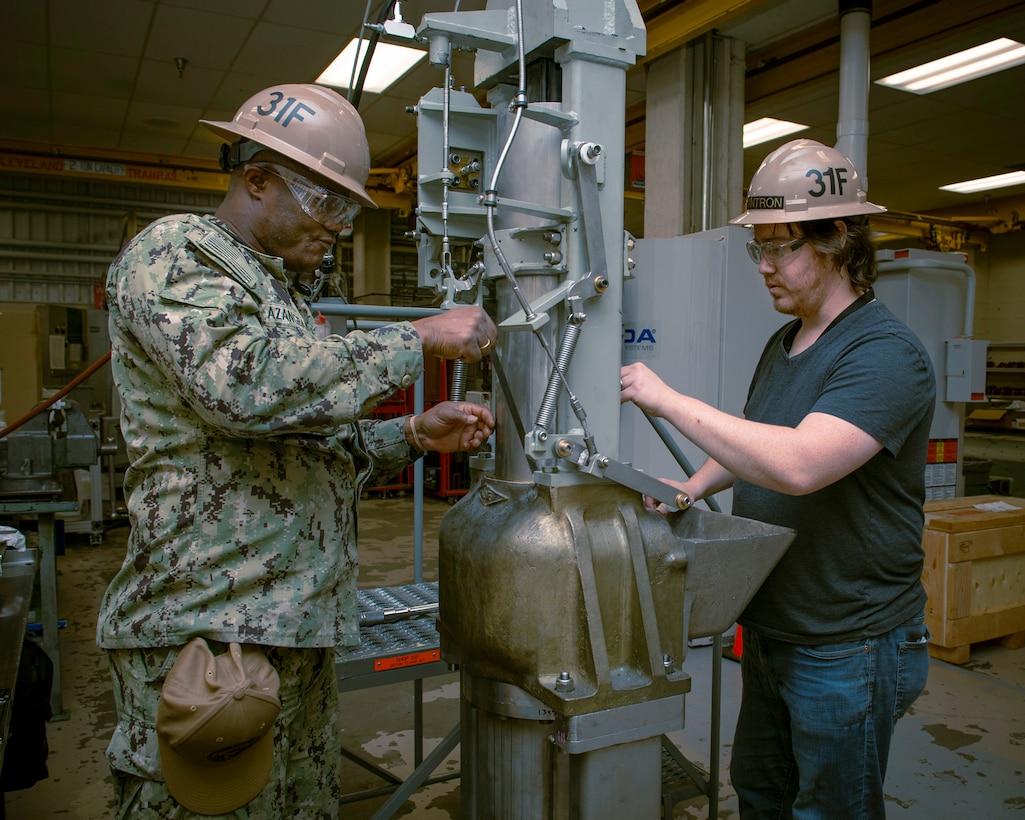 Machinish Mate 1st Class Simplice Azangban, left, and Marine Machinery Mechanic Dylan Scranton overhaul a trash compactor at Trident Refit Facility, Bangor (TRFB).