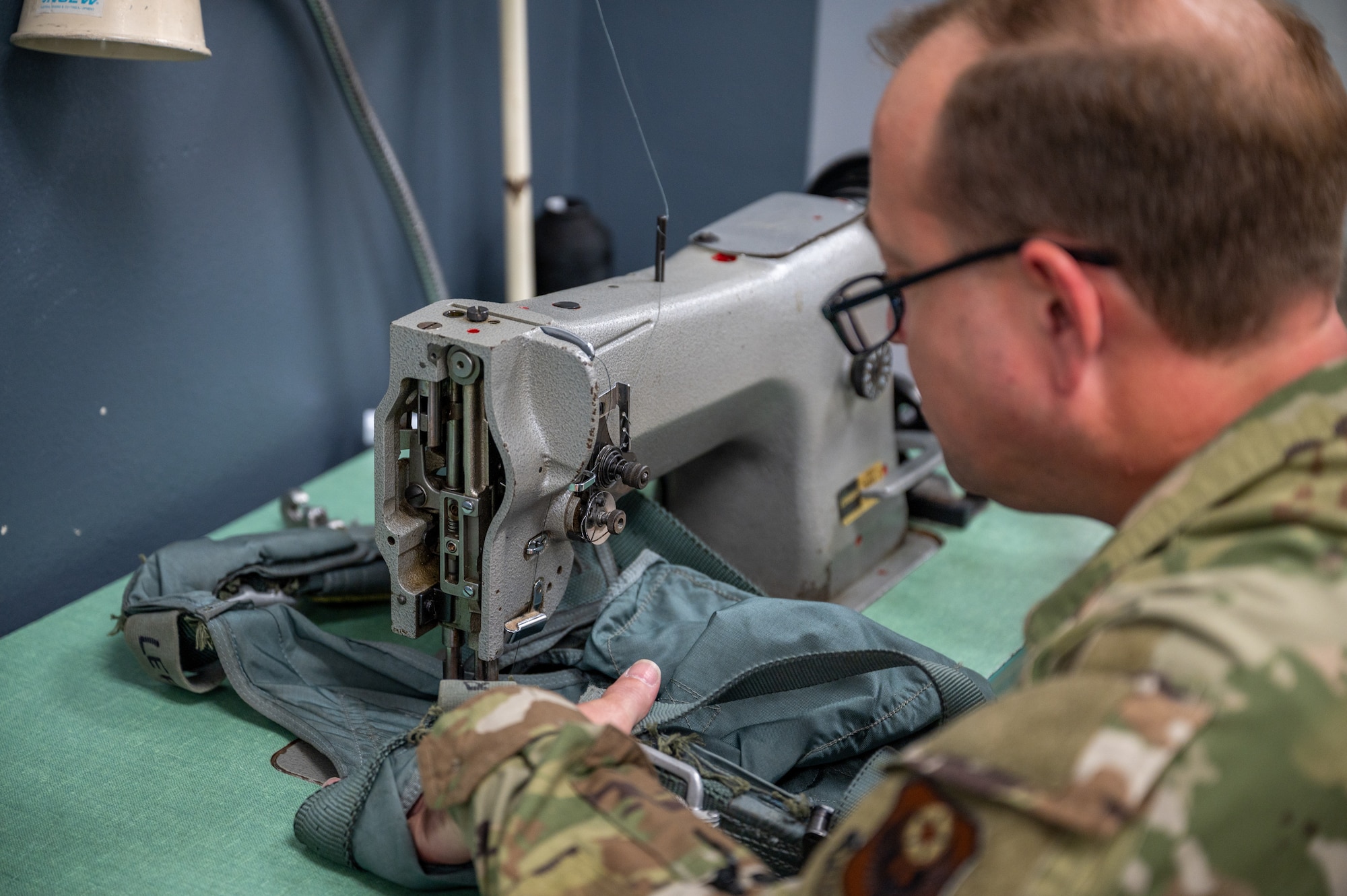 An Air Force Aircrew Flight Equipment technician repairs a restraint harness with a sewing machine at Hurlburt Field.