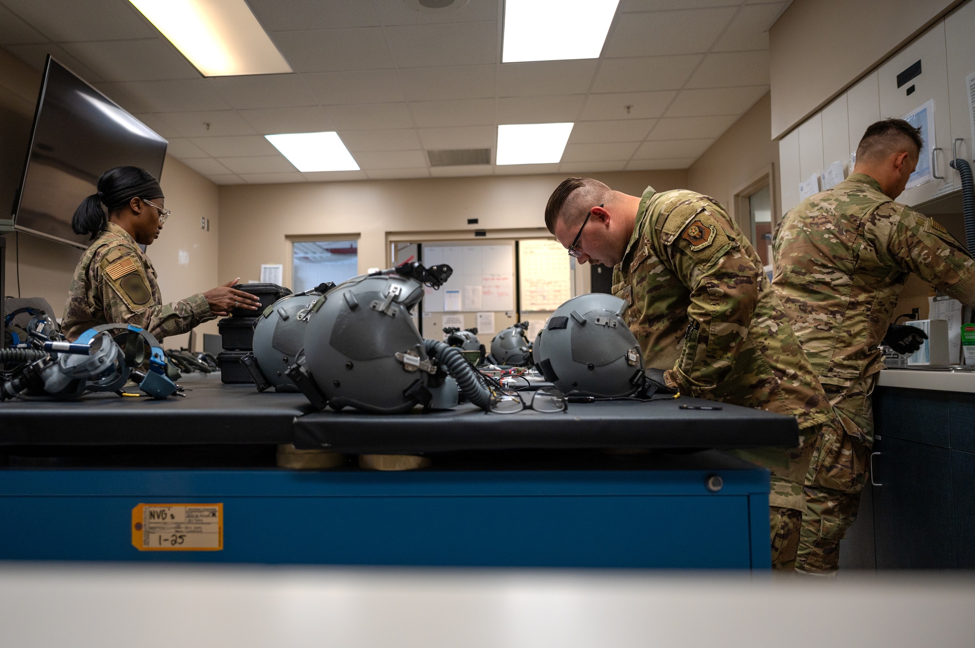 A wide-shot of Aircrew Flight Equipment technicians inspecting flight helmets and night vision goggles at Hurlburt Field.