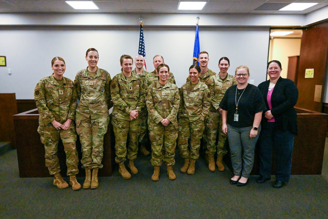 Airmen from the 97th Air Mobility Wing Judge Advocate flight pose for a photo in the courtroom to commemorate the end of Law Week at Altus Air Force Base, Oklahoma, May 2, 2025. The legal office provides eligible individuals with services such as wills, powers of attorney, advance medical directives, notarizations, and guidance on laws including family law, landlord-tenant issues, consumer protection, immigration, crime victim assistance, taxes, and more. (U.S. Air Force photo by Senior Airman Kari Degraffenreed)