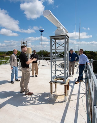 Naval Information Warfare Center (NIWC) Atlantic employee Jay Hughes (right) discusses NIWC’s facility and the role it plays in an upcoming experiment called Southern Lightning which is being held on Sullivan’s Island with the Mayor Patrick O’Neil (sunglasses) and Town Administrator Joe Henderson (light blue shirt) along with NIWC’s commanding officer Captain Matthew O’Neal and NIWC employee Christian Martin.
