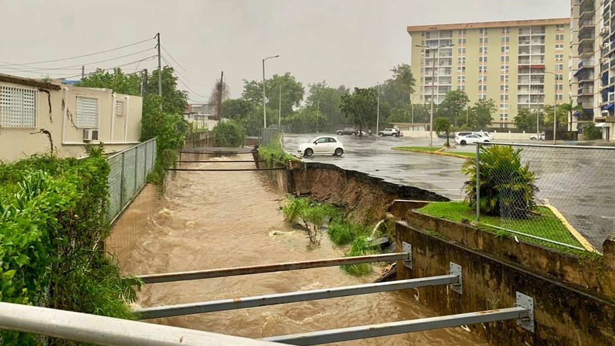 During a rainstorm, the edge of a parking lot has fallen into the river.