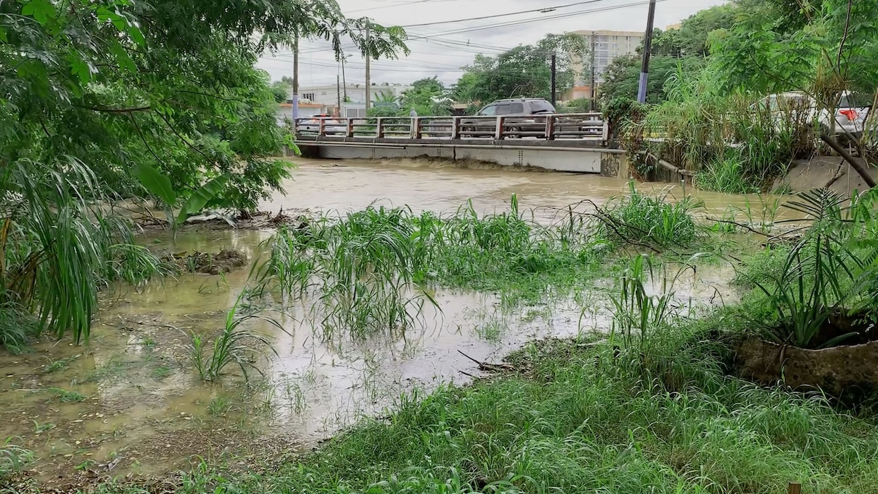 Floodwater in a river reaching the top of a bridge.