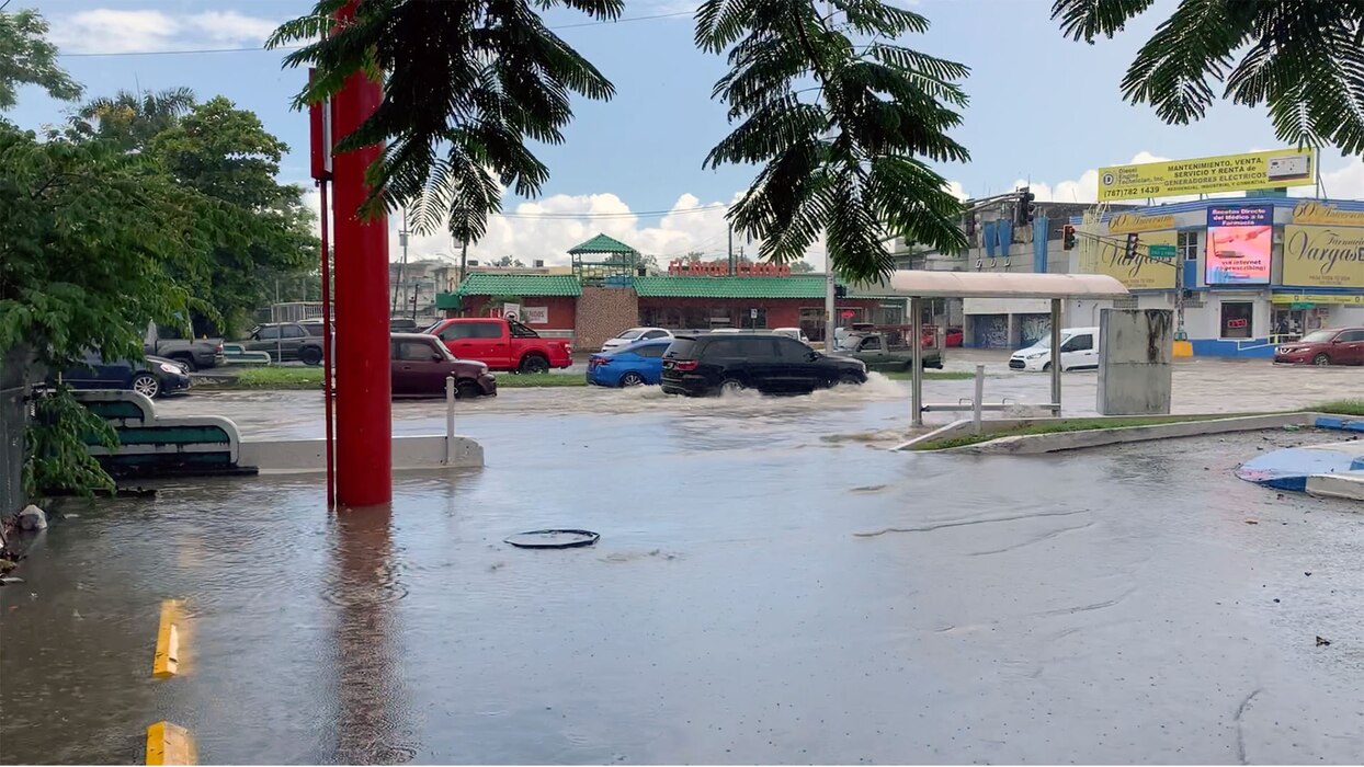 Two feet of flood water in a street with cars driving.