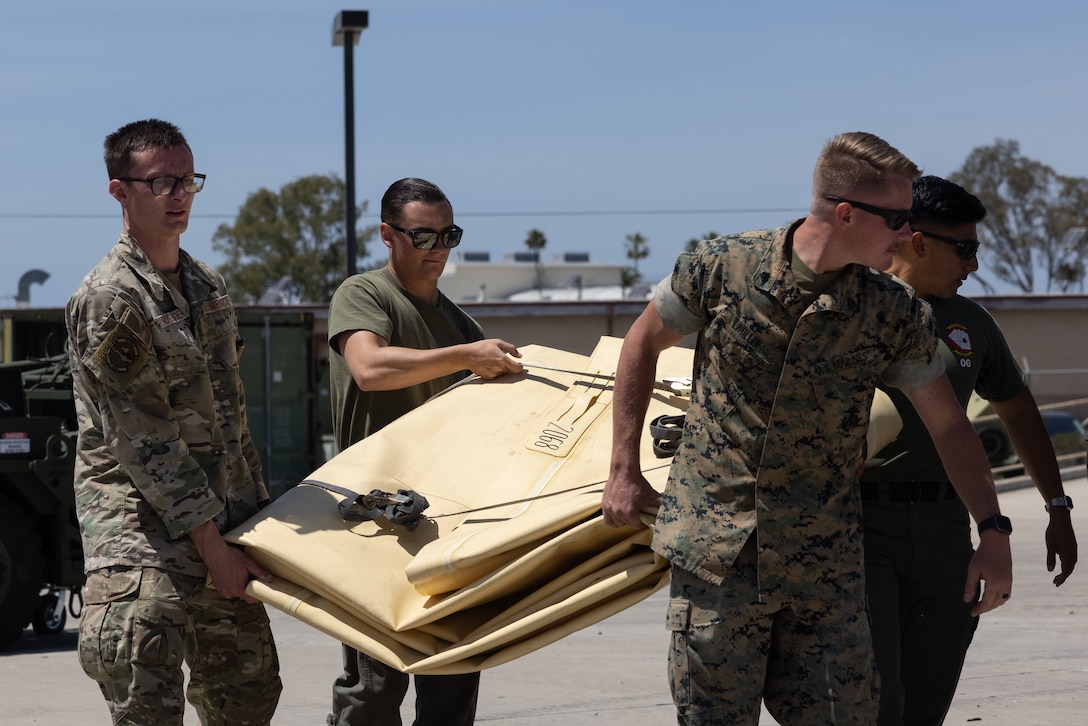U.S. Marines and U.S. Airmen from the 27th Special Operations Mission Support Group, move a collapsible fuel tank during Tactical Air-Ground Refueling System New Equipment Training at Marine Corps Air Station Miramar, California, April 24, 2025.  The TAGRS, an expeditionary Marine Corps-exclusive asset, is a compact mobile refueling system designed to expand the capabilities of Marine Corps’ Forward Arming and Refueling Points and Expeditionary Advanced Base Operations. TAGRS support refueling operations in forward areas and remote locations. (U.S. Marine Corps photo by Lance Cpl. Samantha Devine)