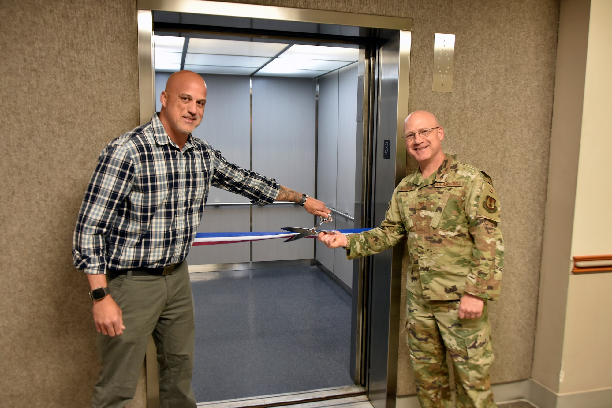 Col. Eric Withrow, Arnold Engineering Development Complex Test Support Division chief, right, and Joseph Baxter, project manager, prepare to cut the ribbon on the new elevator in the Administration and Engineering Building at Arnold Air Force Base, Tenn., May 5, 2025. Arnold AFB is the headquarters of AEDC. The process of replacing the elevator was a two-year effort overseen by the AEDC Civil Engineering Branch. The previous elevator had been in place since construction of the building and was originally intended to serve as a cargo elevator. (U.S. Air Force photo by Bradley Hicks)