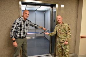 Col. Eric Withrow, Arnold Engineering Development Complex Test Support Division chief, right, and Joseph Baxter, project manager, prepare to cut the ribbon on the new elevator in the Administration and Engineering Building at Arnold Air Force Base, Tenn., May 5, 2025. Arnold AFB is the headquarters of AEDC. The process of replacing the elevator was a two-year effort overseen by the AEDC Civil Engineering Branch. The previous elevator had been in place since construction of the building and was originally intended to serve as a cargo elevator. (U.S. Air Force photo by Bradley Hicks)