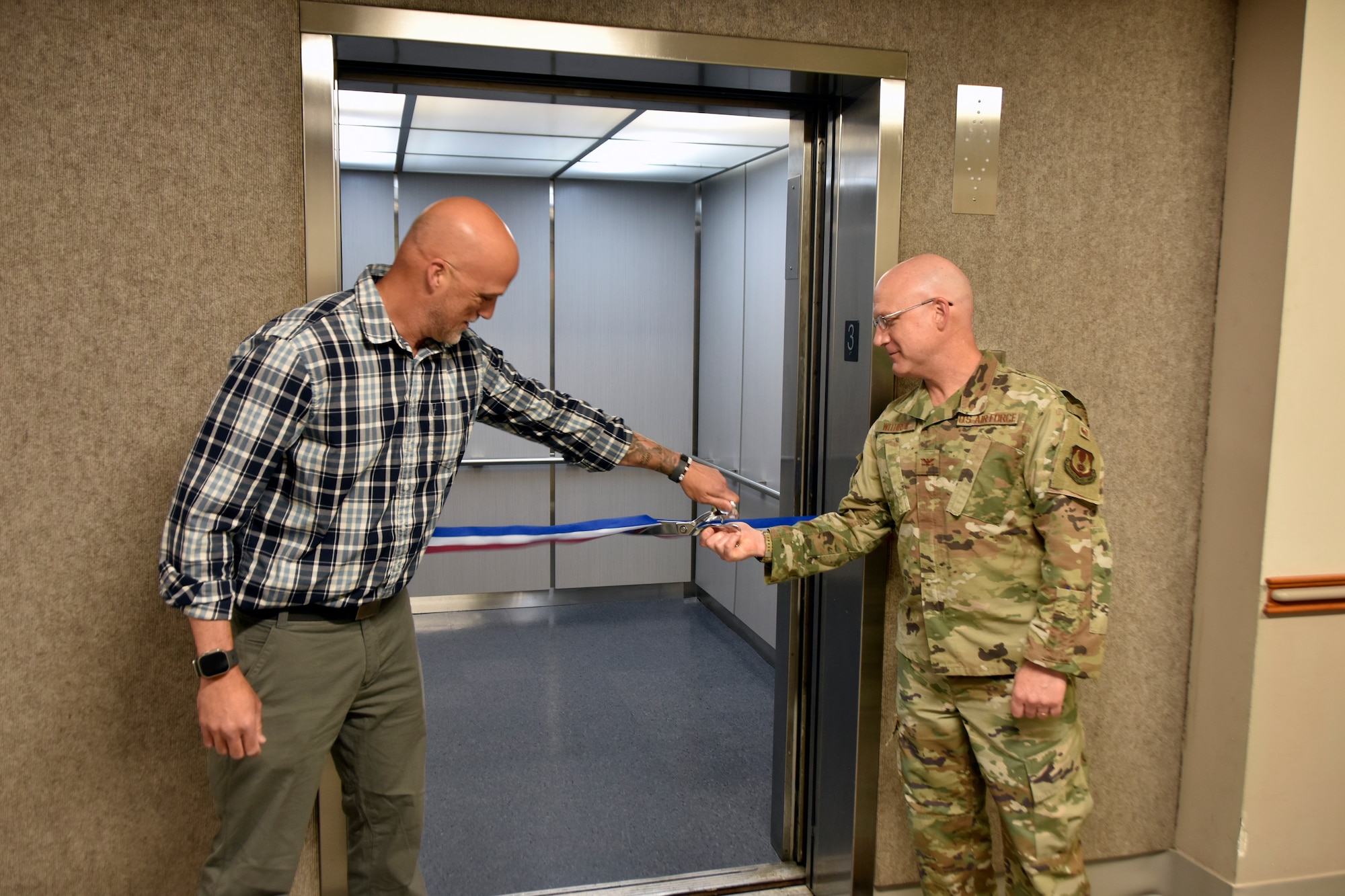 Col. Eric Withrow, Arnold Engineering Development Complex Test Support Division chief, right, and Joseph Baxter, project manager, cut the ribbon on the new elevator in the Administration and Engineering Building at Arnold Air Force Base, Tenn., May 5, 2025. Arnold AFB is the headquarters of AEDC. The process of replacing the elevator was a two-year effort overseen by the AEDC Civil Engineering Branch. The previous elevator had been in place since construction of the building and was originally intended to serve as a cargo elevator. (U.S. Air Force photo by Bradley Hicks)