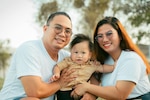 Man and woman smile while holding a baby.