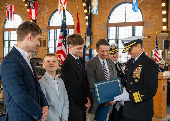 (250411-N-IX644-1009) ANNAPOLIS, Md. Rear Adm. Rick Freedman, right, Navy Deputy Surgeon General and Deputy Chief, Bureau of Medicine and Surgery, presents Capt. Lydia Doye’s family with letters of appreciation during Doye’s retirement ceremony in Dahlgren Hall at the United States Naval Academy, April 11, 2025. Doye served in the Navy for 27 years, building, training, and developing Sailors as a pilot and later as a human resources officer. (U.S. Navy photo by Mass Communication Specialist 2nd Class Sasha Ambrose)