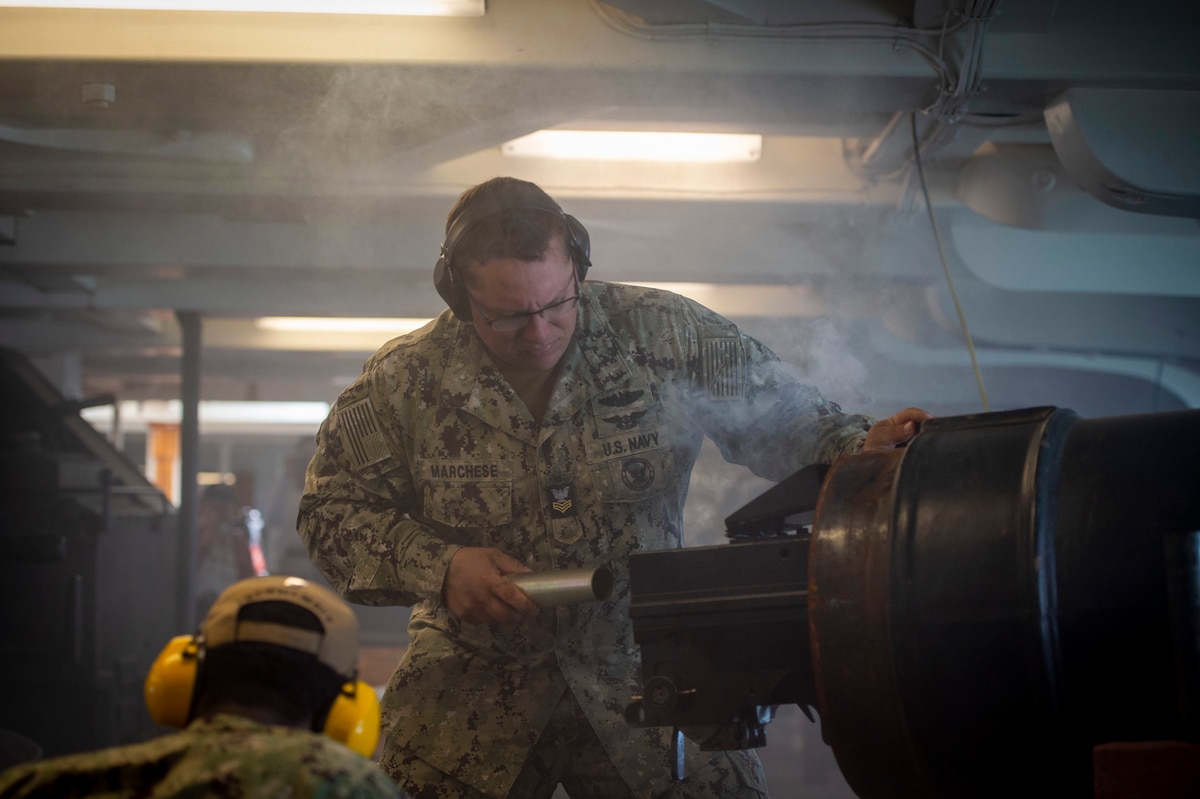 Two sailors simulate lighting canons with smoke below deck on an old ship.