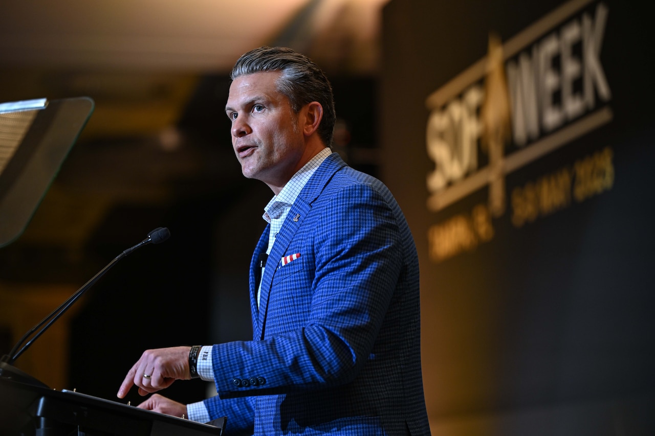 A side view of the defense secretary speaking on a stage.