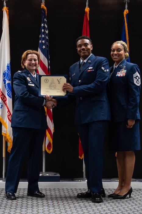 U.S. Air Force Airman 1st Class Christyan Campbell, 17th Force Support Squadron, receives his certificate from Col. Angelina Maguinness, 17th TRW commander, and Chief Master Sgt. Khamillia Washington, 17th TRW command chief, during the Goodfellow Base Honor Guard class 25-Alpha graduation ceremony at the Powell Event Center, Goodfellow Air Force Base, Texas, May 2, 2025. Honor Guard graduates go on to represent the Air Force and all Airmen who ever served as ceremonial guardsmen. (U.S. Air Force photo by Airman 1st Class Brian Lummus)