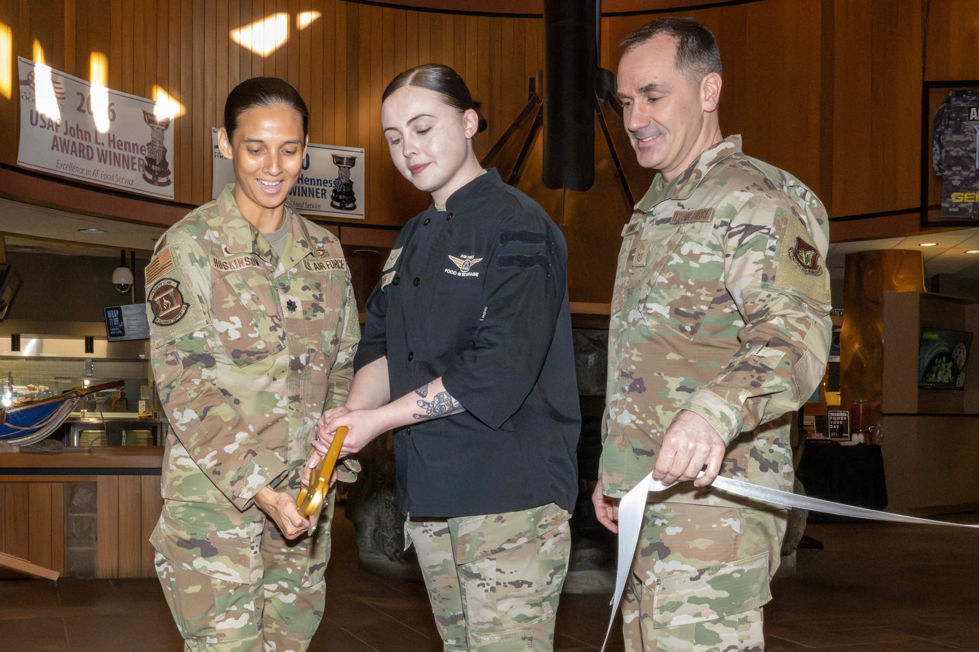 (From left) U.S. Air Force Lt. Col. Veronica Hoskinson, 673d Force Support Squadron commander, Airman 1st Class Adeline Amidon, a food service apprentice assigned to the 673d FSS, and Chief Master Sgt. Jason Brandy, 673d FSS senior enlisted leader, cut a ribbon symbolizing an improved Iditarod Dining Facility at Joint Base Elmendorf-Richardson, Alaska, May 5.