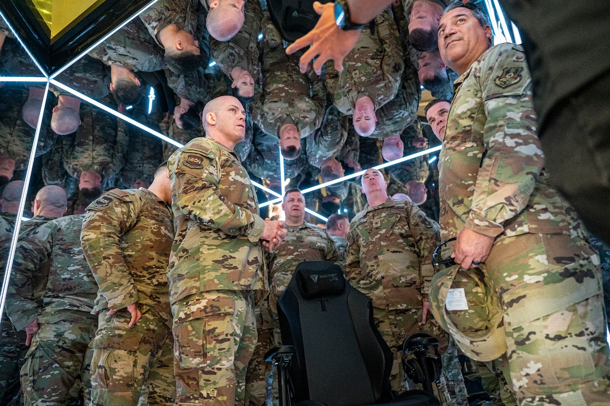 386th AEW leadership team explore the interior reflective cube of the MindGym, reflections and positions scattered across the frame