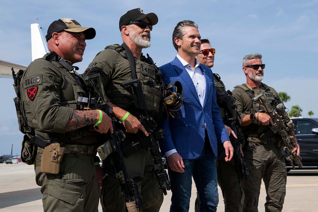 Defense Secretary Pete Hegseth stands for a photo on a flight line with Department of Homeland Security personnel.