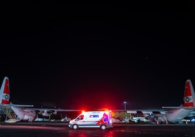 Emergency medical services personnel wait in an ambulance behind two Coast Guard Air Station Barbers Point HC-130 Hercules airplanes on the ramp at the air station in Kapolei, Hawaii, March 20, 2025. An Air Station Barbers Point HC-130 Hercules airplane crew conducted a medical transport for an ailing man on Kwajalein Atoll. 